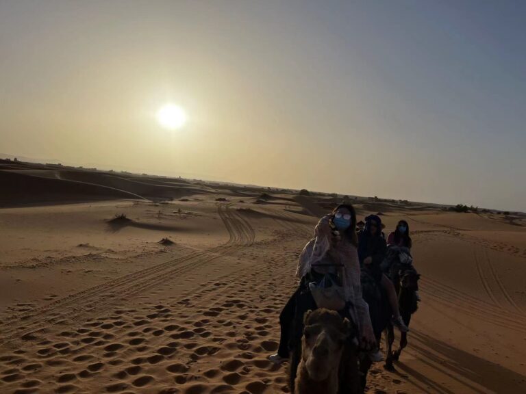 What to Wear for Camel Riding Traveler riding a camel safely with a desert guide in Morocco