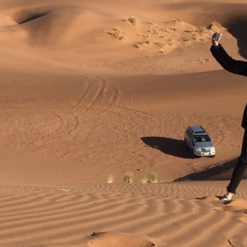 Traveler walking through the Erg Chegaga desert dunes in Morocco